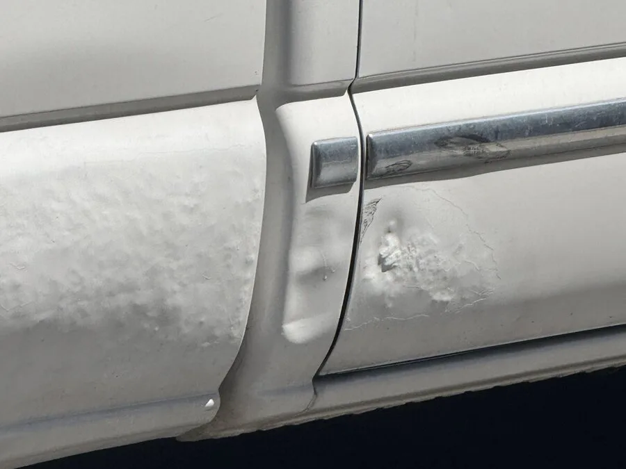 Body filler bubbling and cracking at a door edge where it was sold as paintless repair