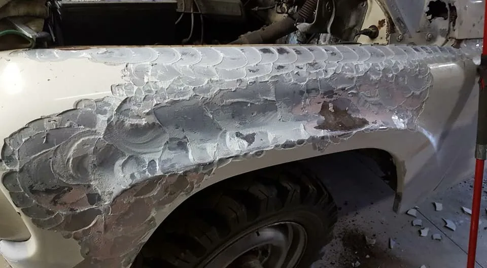An entire truck fender buried under rough-sanded body filler
