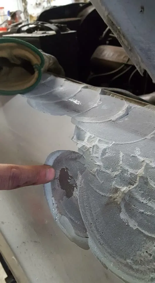 Thick layers of body filler sanded over a rusted-through panel with a hole still showing