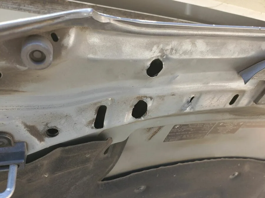 Several access holes drilled through an inner panel and left open, now rusting