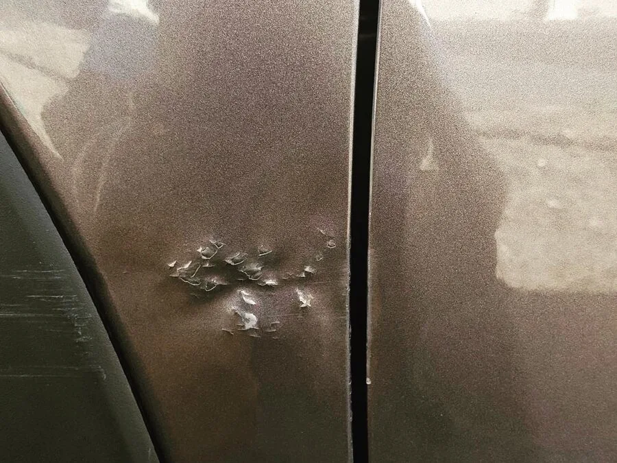 Fender paint cracked into a starburst of flakes after a dent was over-pushed from behind